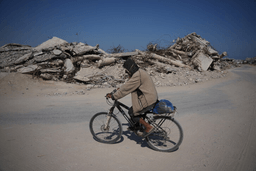 A Palestinian man rides his bicycle by the rubble of buildings that were destroyed during the Israel Hamas war, in Khan Younis, southern Gaza Strip, Friday, July 31, 2026. (AP Photo/Abdel Kareem Hana)