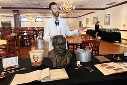 Auctioneer Jonathan Klunk gestures to a display of personal items owned by KFC founder Harland Sanders, Wednesday, July 22, 2026, in Shelbyville, Ky. (AP Photo/Dylan Lovan)